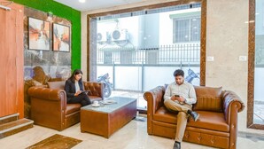 A lobby with leather sofas, a glass coffee table, and artwork on the wall. - FabHotel Dreamworld Residency (Barasat)