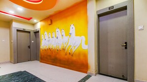Un couloir orné d’une fresque représentant des chevaux blancs, deux portes portant les numéros 203 et 205, et un tapis à motifs de marbre.