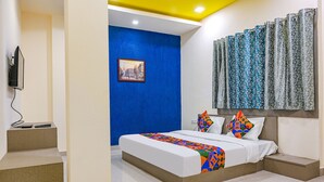 Une chambre d’hôtel moderne avec un grand lit, une télévision et un mur d’accent bleu.