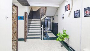 A hallway with a staircase, a plant, and framed pictures on the walls. - Fabhotel Rivlet Inn (Gurugram)