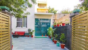 A courtyard with a bench, potted plants, and a building entrance. - Fabhotel Rivlet Inn (Gurugram)