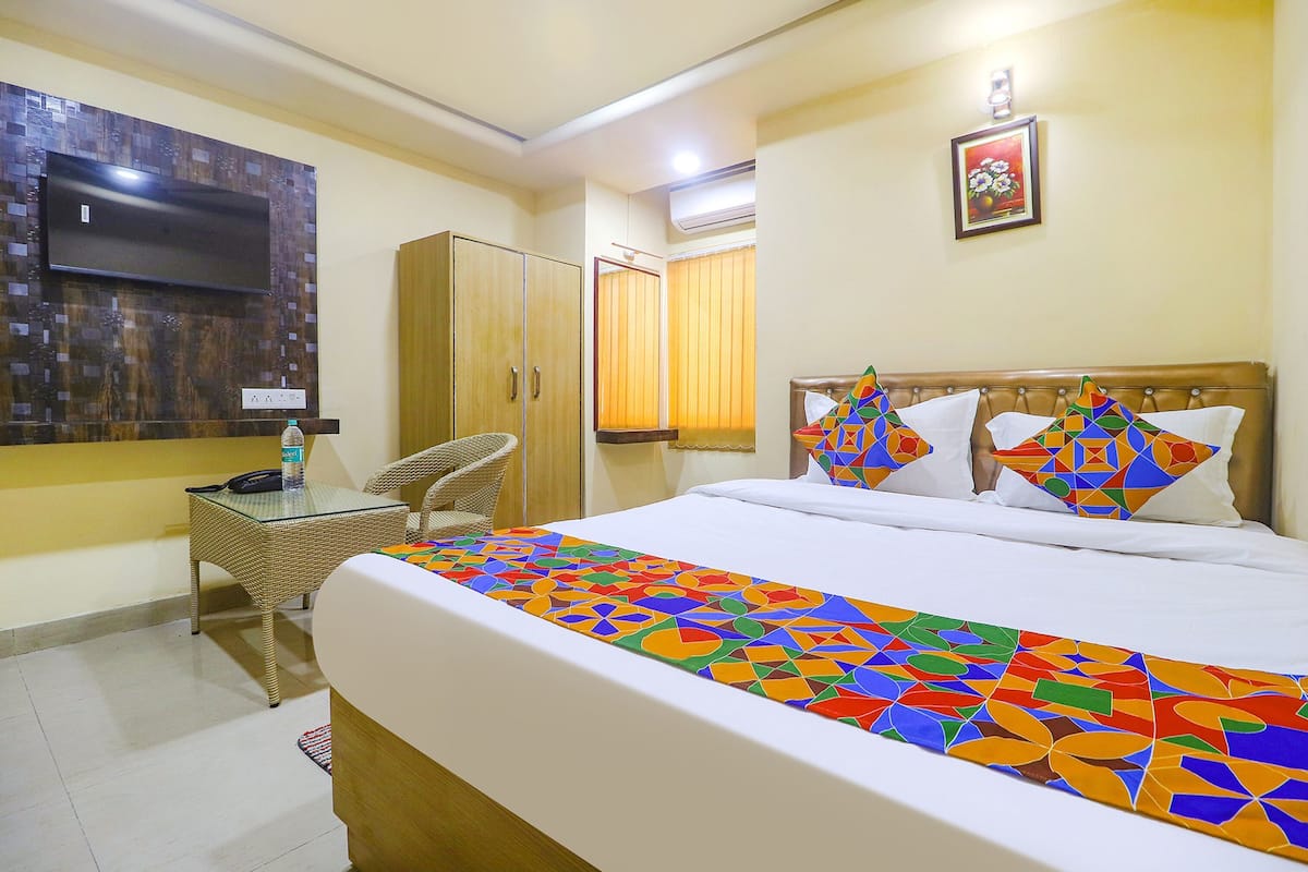 A hotel room with a bed, a television, a wardrobe, and a chair.