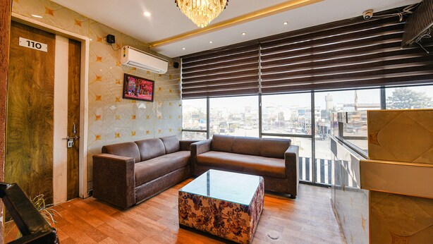 A modern lobby with a large window, a chandelier, and a brown leather sofa. - Fabhotel The Dreams (Kharar)