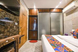 Habitación de hotel con cama, armario de madera, baño con espejo y zona de ducha.