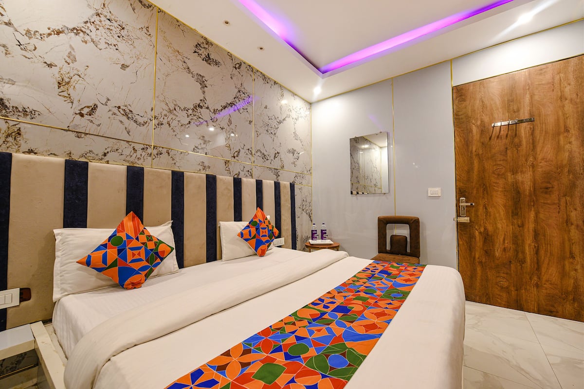 A modern hotel room with a large bed, a wooden wardrobe, and a marble wall.