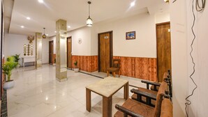 A hotel lobby with a reception desk, a seating area with a wooden bench, a small table, and a potted plant. - Fabhotel The Dreams (Kharar)