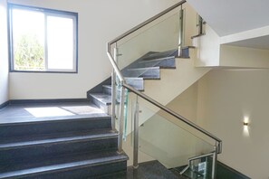 Eine moderne Treppe mit Glasgeländern und Blick auf Grünflächen.