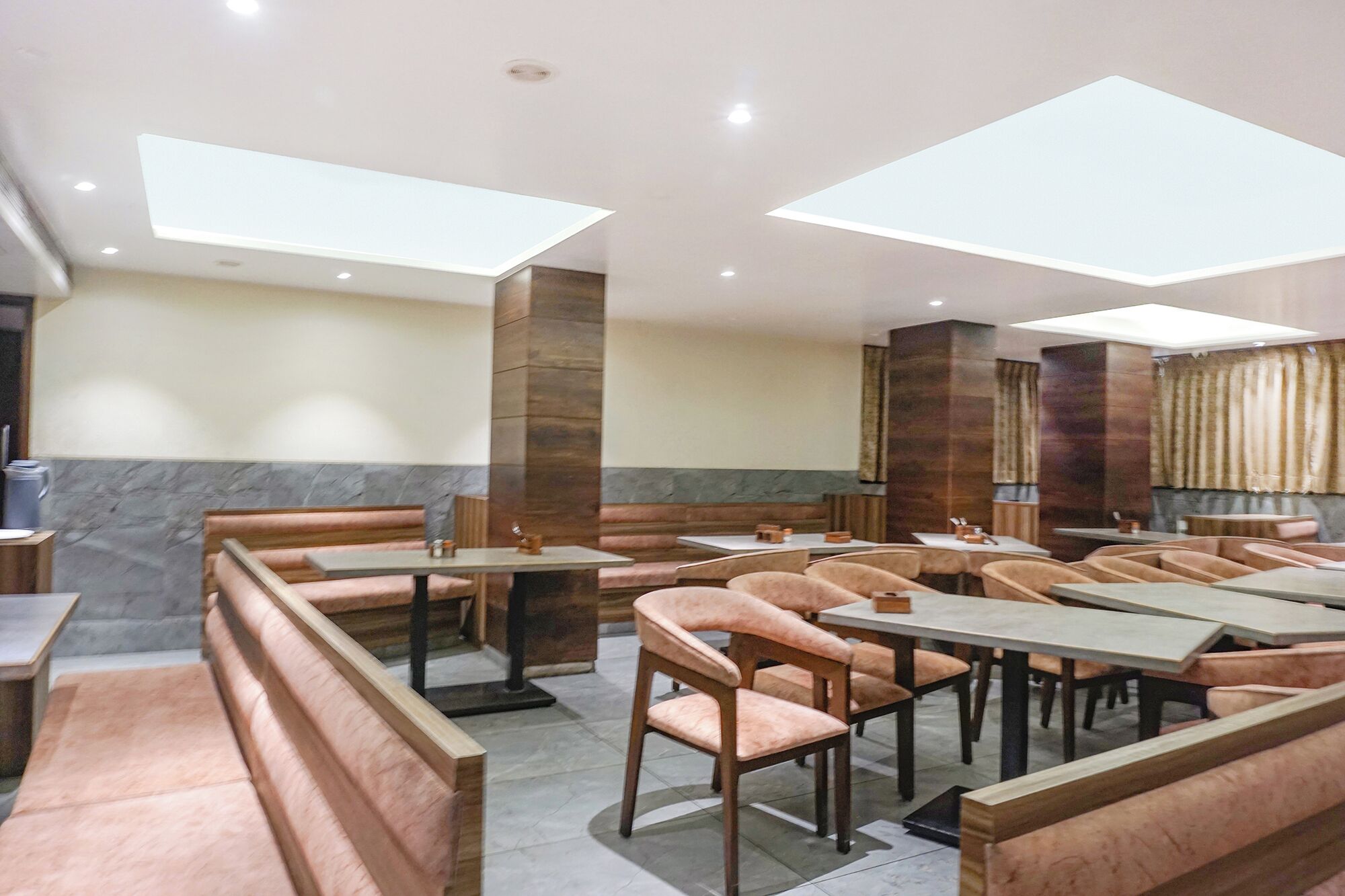 A restaurant with booths and tables, recessed ceiling lights, and a stone accent wall.
