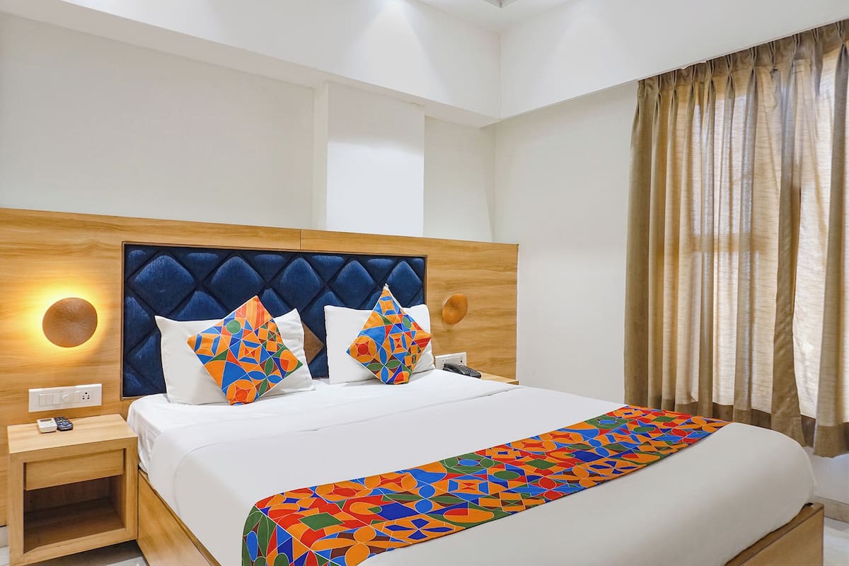 A hotel room with a large bed, a wooden headboard, two bedside tables, and a nightstand.