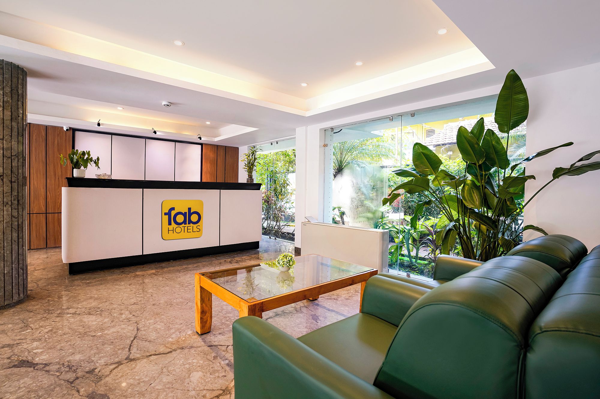 Zona de recepción de hotel con diseño moderno, que incluye un mostrador de recepción, área de estar y vistas al exterior.