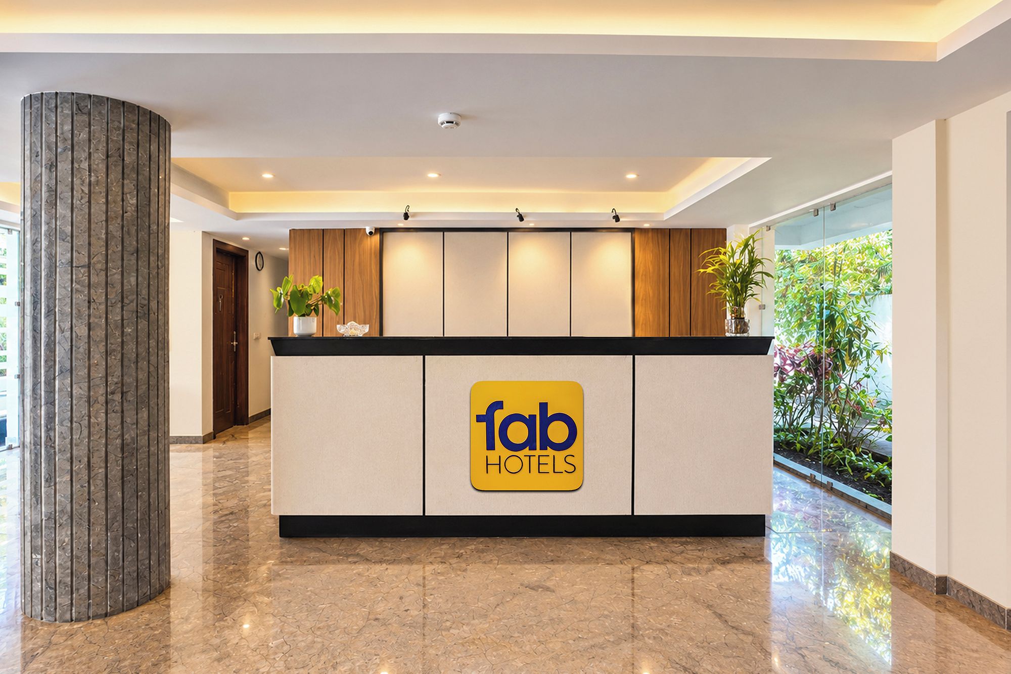 Una mesa de recepción con el logotipo de 'fab hotels' y una planta en maceta encima.