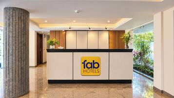 Una mesa de recepción con el logotipo de 'fab hotels' y una planta en maceta encima.