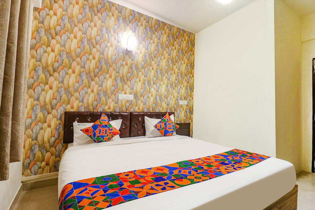 A hotel room with a large bed, a patterned wall, and a modern headboard.