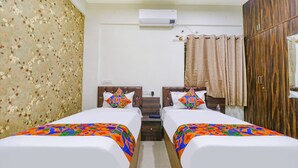 A hotel room with two beds, a wardrobe, an air conditioning unit, and a shower curtain. - Fabhotel E City Inn (Bengaluru)