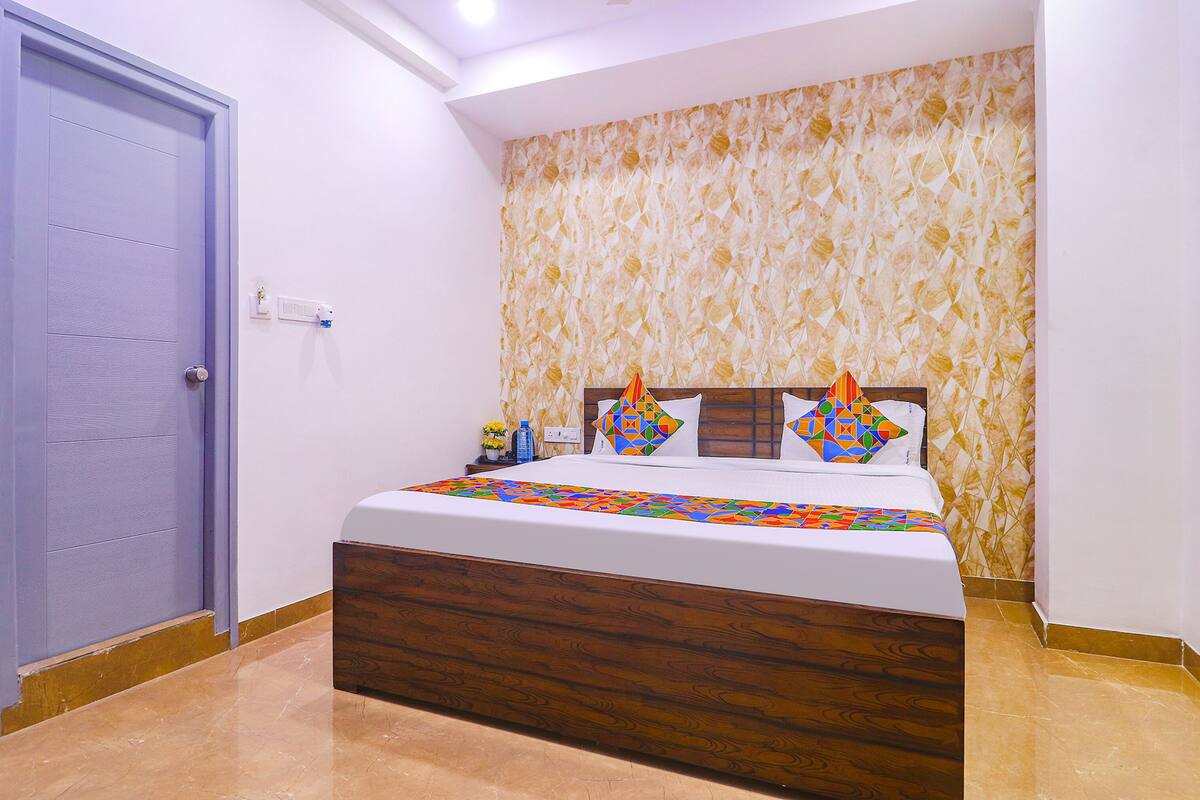 A bedroom with a wooden bed frame, a patterned wallpaper, and a blue door.