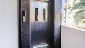 An elevator with a metallic interior and a control panel on the wall. - FabExpress The Dream Elite (Hyderabad)