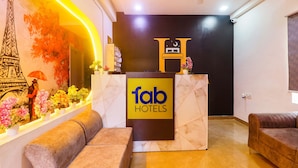 A hotel reception area with a marble counter, plush seating, and a decorative wall with a Parisian theme. - FabExpress The Dream Elite (Hyderabad)