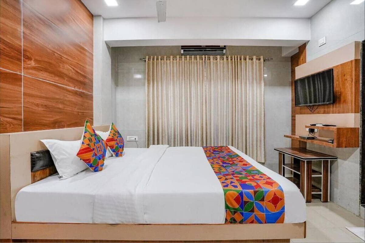 Une chambre d’hôtel moderne avec un grand lit, un téléviseur fixé au mur et un petit bureau.