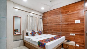 A modern bedroom with a wooden bed frame, a bedside table, a mirror, and a ceiling fan. - FabHotel White Gold (Navi Mumbai)