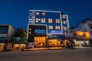 Un edificio moderno con un llamativo letrero de 'fab hotels', con fachada de vidrio y entrada iluminada.