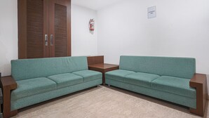 Una habitació amb dos sofàs verds, un armari de fusta i una taula petita.