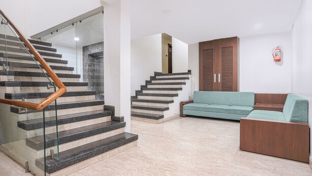 Un interior modern amb una escala, un sofà verd i armaris de fusta.