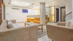 Un vestíbul d'hotel amb una taquilla de recepció, sofàs, una taula de café i un penjador.