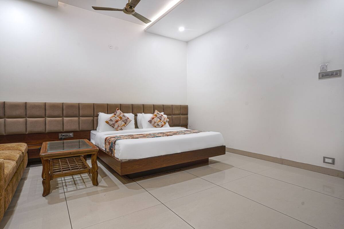Une chambre à coucher comprenant un lit, une table de chevet en bois, un ventilateur de plafond et un climatiseur fixé au mur.