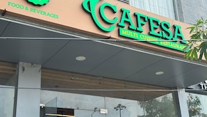 A cafe with a green and yellow signboard, a glass entrance, and a modern building facade.