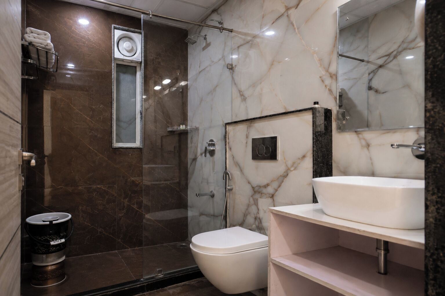 Un baño moderno con ducha de mármol, inodoro y lavamanos.