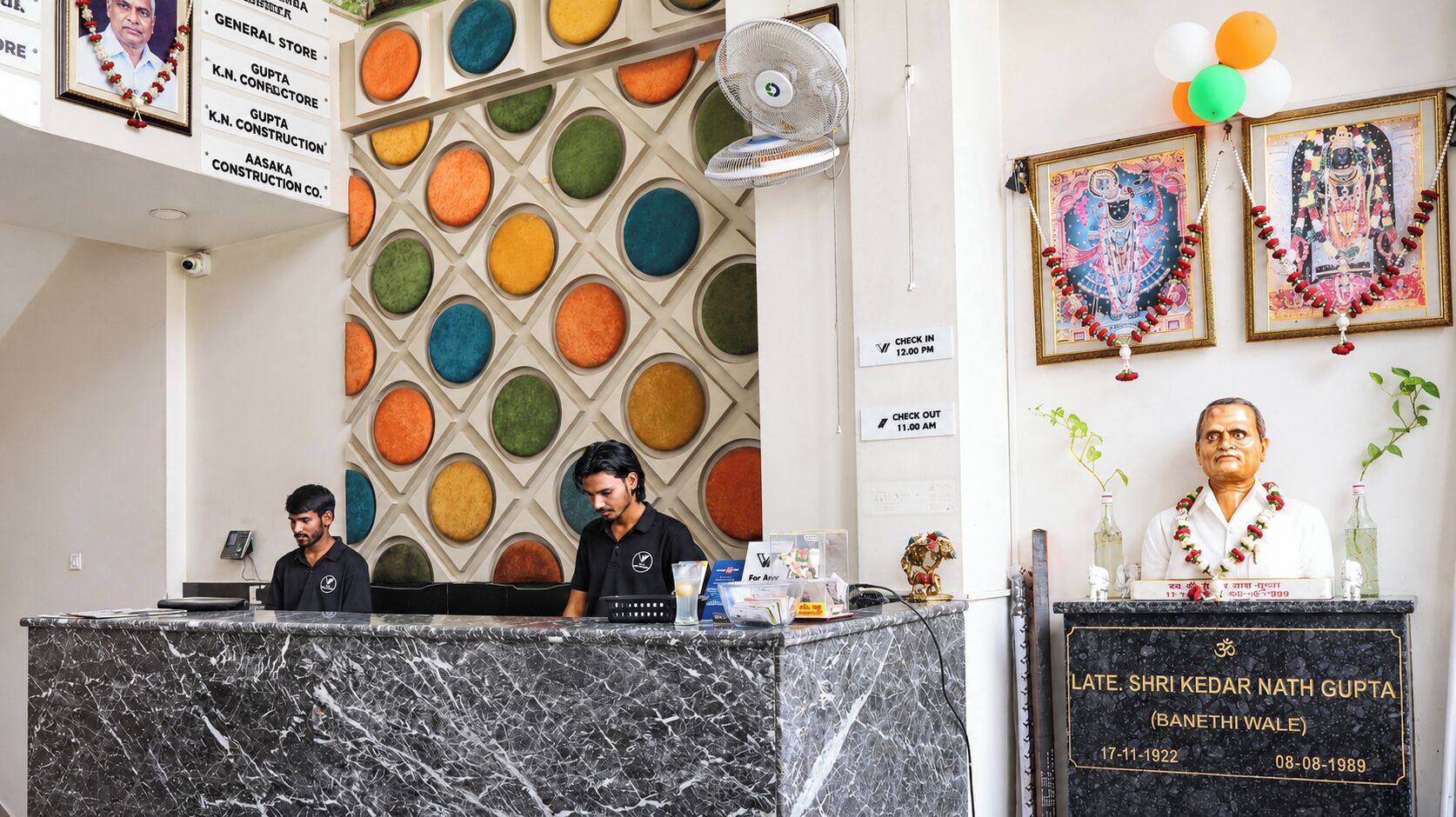 A hotel reception area with a marble counter, a wall with circular patterns, and framed artwork.
