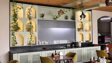 Un interior de restaurante con una barra negra, armarios blancos y sillas amarillas.