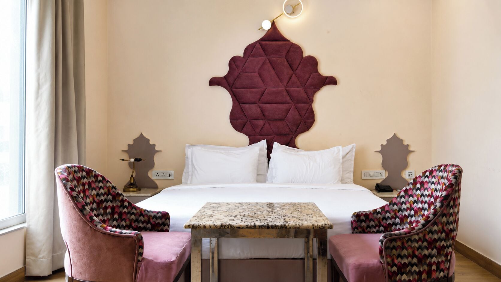 Habitación de hotel con cama, dos sillones, una mesita y un adorno en la pared.