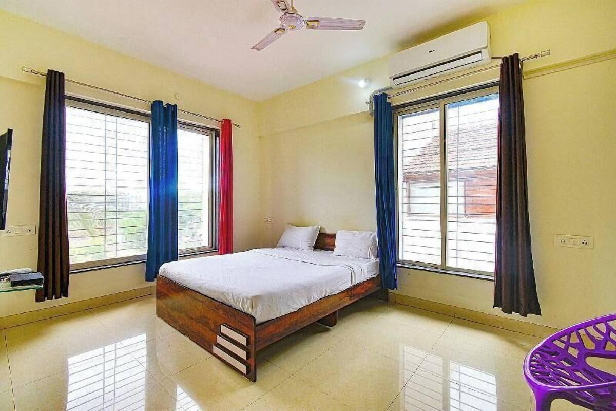 A bedroom with a bed, a ceiling fan, an air conditioner, and a window with curtains.