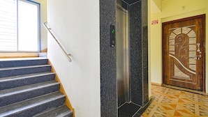 Una escalera con barandilla, un ascensor y una puerta con letrero de 'EXIT'.