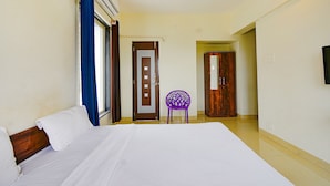 Habitación de hotel con una cama grande, una ventana con cortinas, un ventilador de techo y una puerta que da a otra habitación.