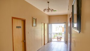 A hallway with a wooden door labeled "CORAL PASSION," a chandelier, and a view of an outdoor balcony with a table and chairs. - Fabhotel Hibiscus Stays (Chennai)