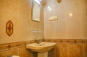 A bathroom with a sink, mirror, and tiled walls. - Fabhotel Hibiscus Stays (Chennai)