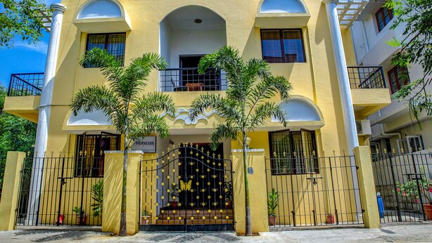 A yellow building with a sign reading "fab hotels" and a gated entrance with decorative elements. - Fabhotel Hibiscus Stays (Chennai)