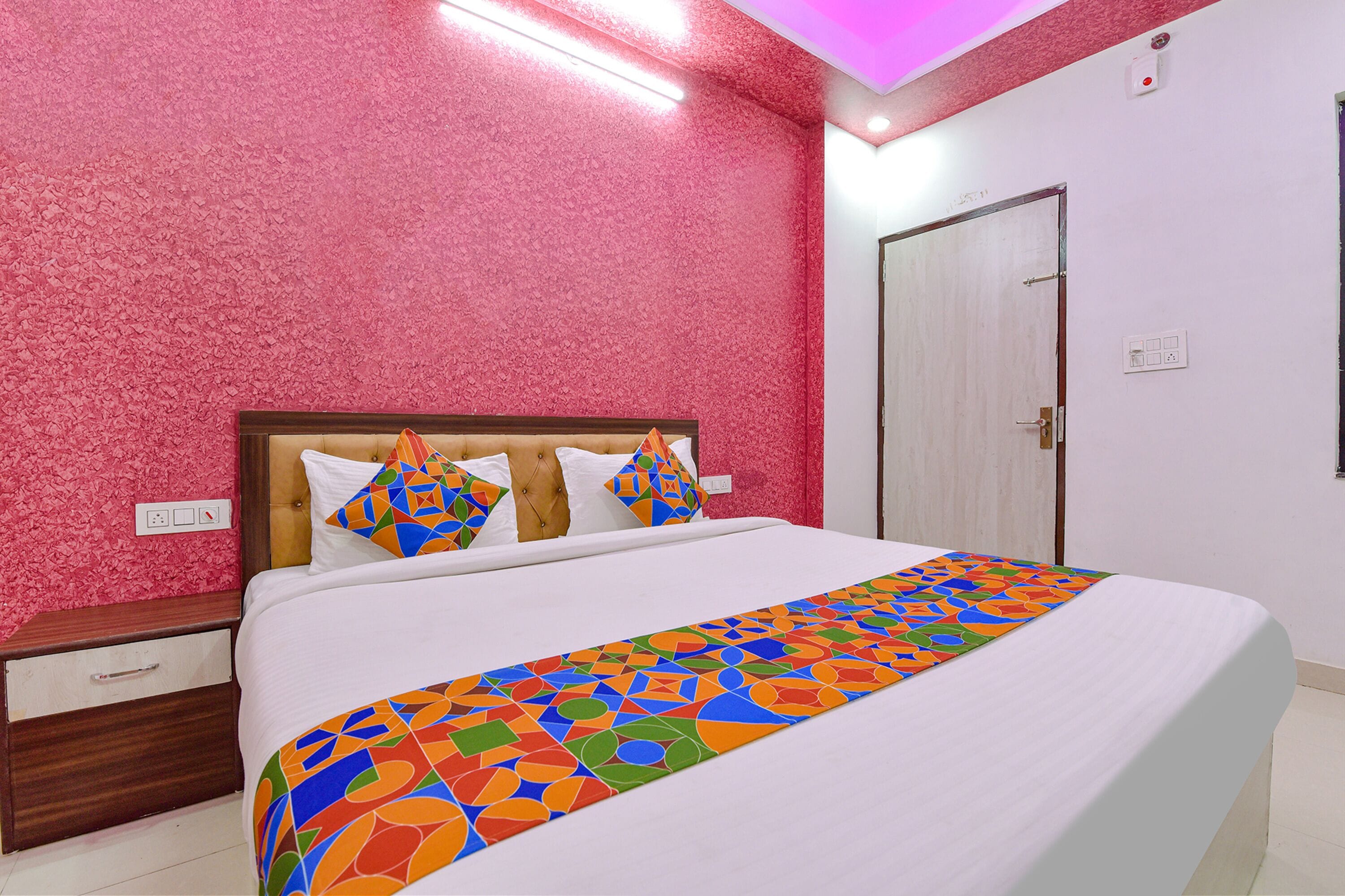 Une chambre à coucher comprenant un lit, une table de chevet, une porte et un mur orné d’un motif texturé.