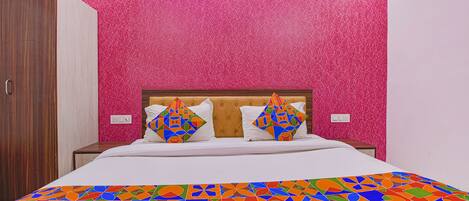 A bed with a colorful geometric-patterned bedspread, a tufted headboard, and two decorative pillows.