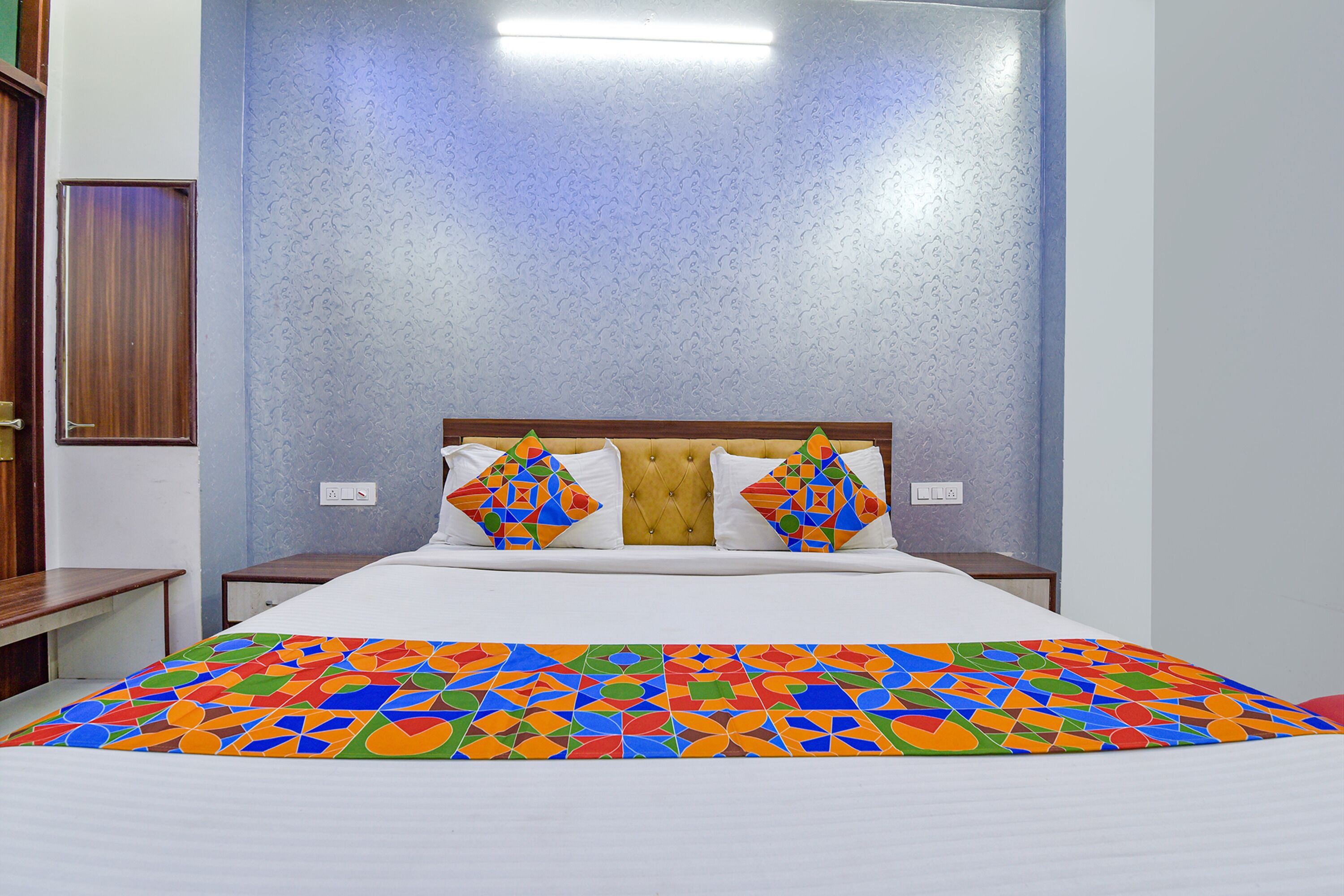Een hotelkamer met een bed, hoofdeinde en nachtkastje.
