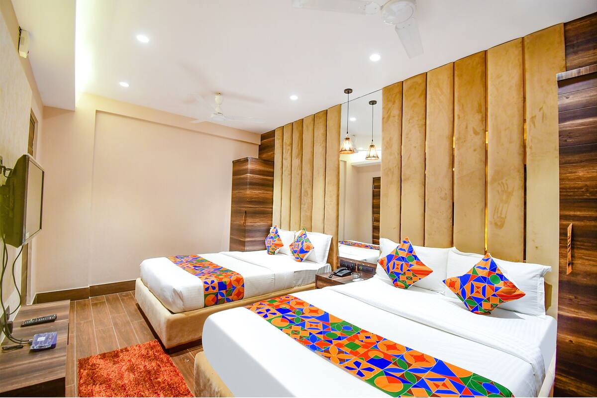 A hotel room with two beds, wooden paneling on the walls, a large mirror, and a red rug.