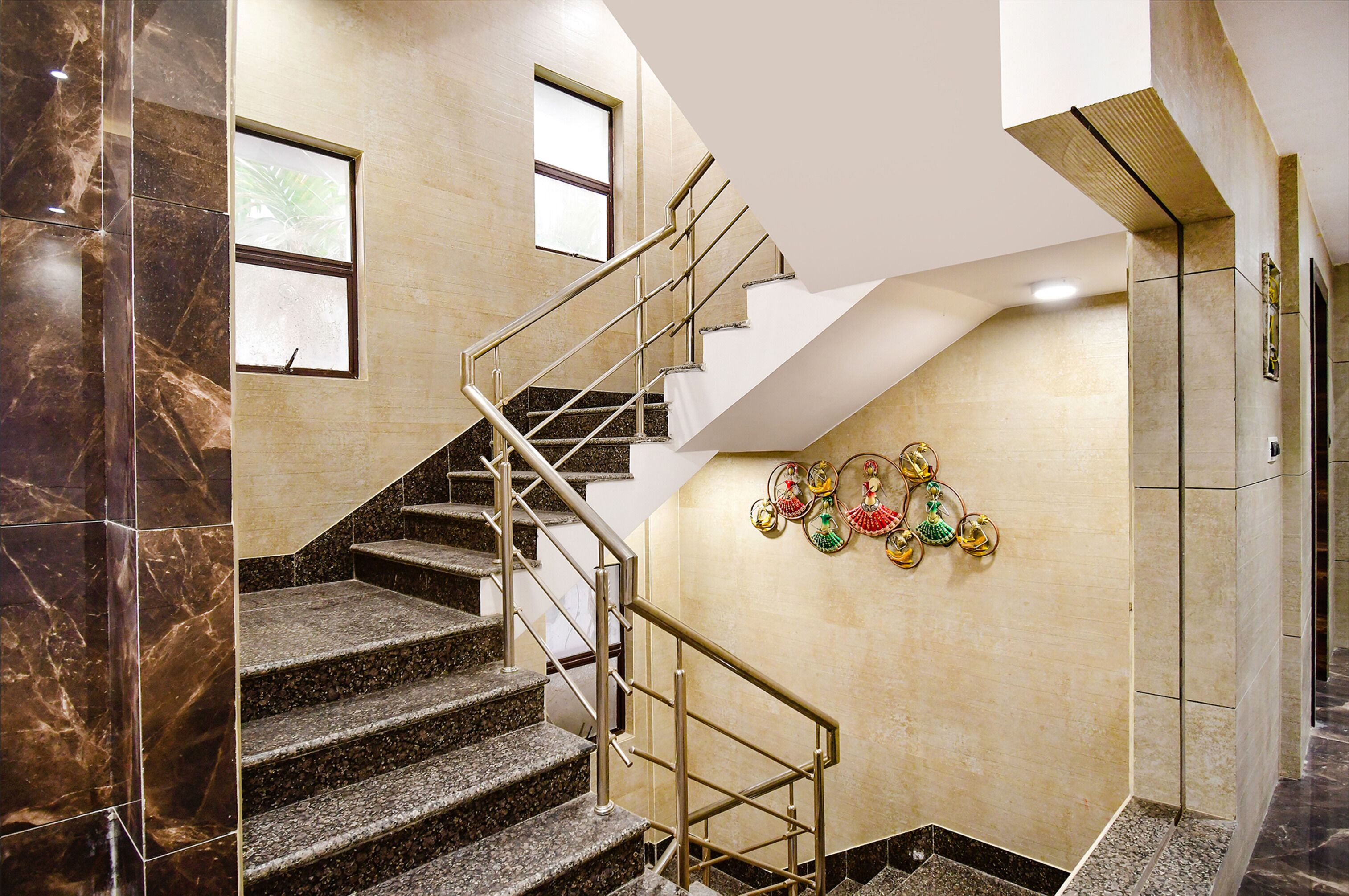 A staircase with marble walls and a handrail, leading to a landing with decorative wall hangings.