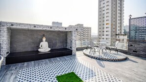 Eine Dachterrasse mit Meditationsbereich, Außenmöbeln und einem gemusterten Boden.
