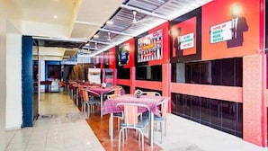 A restaurant with tables and chairs, a red and black color scheme, and signs on the walls. - Fabhotel Ranjanas (Paud)
