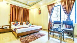 A hotel room with a bed, a small table, and a chair. - Fabhotel Ranjanas (Paud)