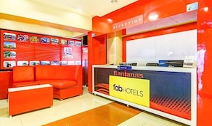 Un área de recepción con un sofá rojo, un mostrador de recepción y una pared con diversas imágenes relacionadas con viajes.