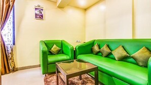 A room with two green sofas, a glass coffee table, and a patterned rug. - Fabhotel Ranjanas (Paud)