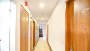 Un pasillo con puertas de madera, suelo de baldosas y una escalera al final.